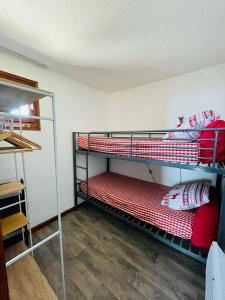Cette chambre comprend 2 lits superposés dotés d'oreillers rouges et blancs. dans l'établissement Les Menuires skis aux pieds, aux Menuires