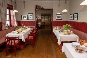 un comedor con mesas blancas y sillas rojas en Landhaus Schulze-Hamann - Hotel garni - en Blunk
