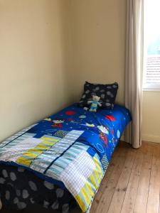 a small bed with a blue comforter with a stuffed animal on it at Agréable maison de ville ,calme avec tous les commerces à 150M in Cherbourg en Cotentin