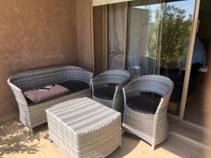 three wicker chairs and a table on a balcony at Au Rez de jardin, Bel appt au sein du golf Montgomery in Marrakesh