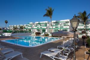 a swimming pool with lounge chairs and a hotel at Nazaret Apartments in Costa Teguise
