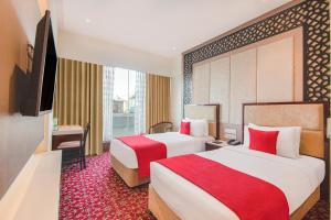 インドールにあるSarovar Portico , Indoreのベッド2台とテレビが備わるホテルルームです。