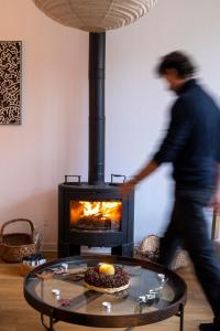 a man walking through a living room with a fireplace at Domaine des Pousses, gîte au coeur d'un village de campagne in Droue-sur-Drouette