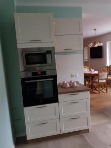 a kitchen with white cabinets and a microwave at Ferienwohnung am Schlosssee. in Penkun