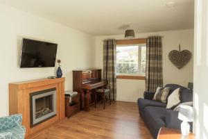a living room with a couch and a television and a piano at No 4 the Highlands in Strathpeffer