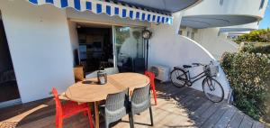een houten tafel en stoelen op een terras met een fiets bij Zen et Mer in Le Grau-du-Roi +24 foto's
