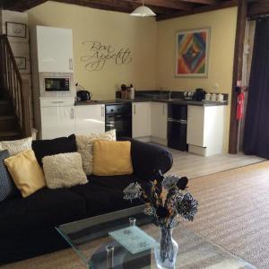 a living room with a black couch and a kitchen at Gites la Charrue in Monsec