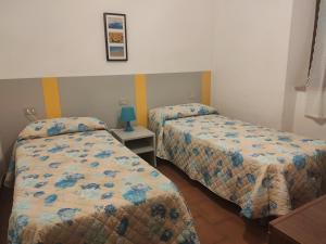 a bedroom with two beds and a table with a lamp at Appartamento Il Girasole in Pomonte