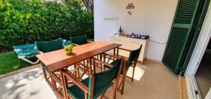 a wooden table with green chairs in a backyard at Casa RISSAGA - Las Golondrinas in Cala'n Bosch
