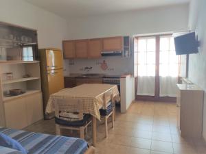 uma cozinha com uma mesa e uma cozinha com um frigorífico em Appartamento Il Nespolo em Pomonte