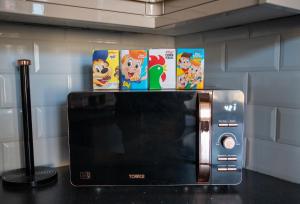 a microwave with two cartoons on top of it at Withnell Stays - Apartment One - Ground Floor - Retro Gaming Machine in Blackpool +16 photos