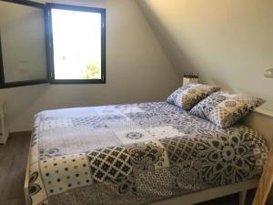 a bedroom with a bed with a comforter and a window at Villa La Baronne-Hauteurs de Beaulieu-sur-Dordogne in Beaulieu-sur-Dordogne