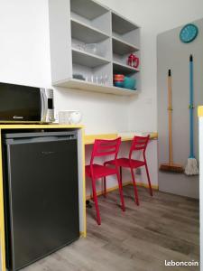 cocina con sillas rojas y encimera con microondas en Résidence Les Volets Bleus: Studio de 30 m² classé 2 *, en Rochefort