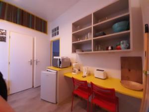 cocina con mesa amarilla y sillas rojas en Résidence Les Volets Bleus: Studio de 30 m² classé 2 *, en Rochefort