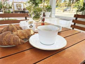 a wooden table with a cup of coffee and bread at Esal Hotel in Durrës