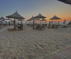 a beach with chairs and umbrellas on the sand at Esal Hotel in Durrës