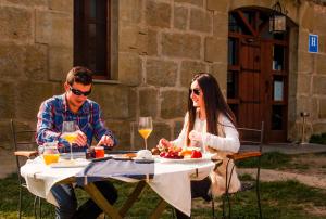 a man and woman sitting at a table with wine glasses at Hotel Boutique Bodegas De Arnes - Adults Only in Graus