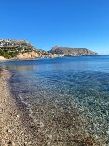 a beach with a rocky shore and the ocean at El jardin Botánico Villa LUZ in Altea