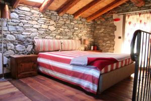 1 dormitorio con cama y pared de piedra en Le Petit Coin De Maison Chante Lune en Introd