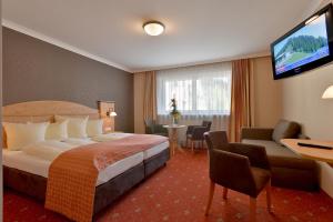 ein Hotelzimmer mit einem Bett und einem Flachbild-TV in der Unterkunft Hotel Mesnerwirt in Westendorf