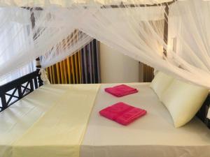 a white bed with two red pillows on it at Coral Palm Villa and Apartment in Unawatuna