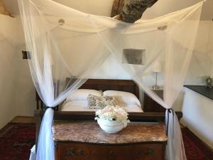 a bedroom with a canopy bed with a table with flowers on it at Pérard Chambres D’Hotes in Caylus