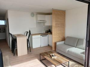 Una sala de estar y una cocina con un sofá y una mesa. en T2 vue exceptionnelle avec accès privé à la plage, wifi, clim - dansnotreappart-com -, en Valras-Plage