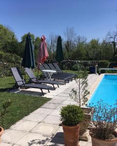 a group of chairs and umbrellas next to a swimming pool at Pérard Chambres D’Hotes in Caylus