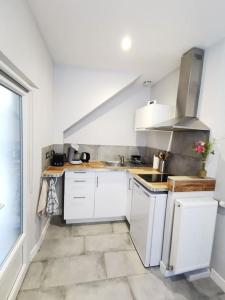 a kitchen with white cabinets and a tile floor at Les bulles d'Ay - Studio in Ay