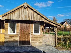 um barracão de madeira com uma porta e uma cerca em 't Hûske em Venhorst