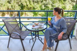 Paradise Hotel في ساموس: امرأة تجلس على طاولة مع كوب من العصير