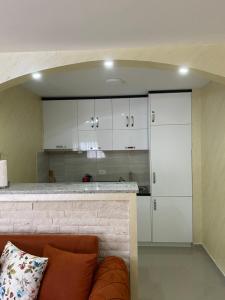 eine Küche mit weißen Schränken und einem Sofa in einem Zimmer in der Unterkunft Brankooo in Bar