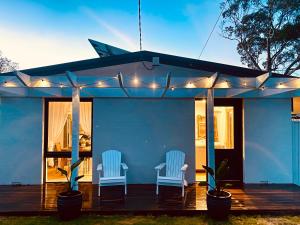 una casa blu con due sedie e luci su una terrazza di Rosebud Lovely House - Mornington Peninsula 3 BR holiday house - Jacuzzi - BBQ - Basketball ring - Beach - Hot springs a Rosebud