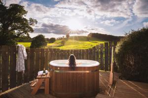 a woman sitting in a hot tub on a deck at Oak Tree Barn in Donyatt