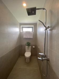 a bathroom with a toilet and a window and a shower at Toro Homestay in Hoi An