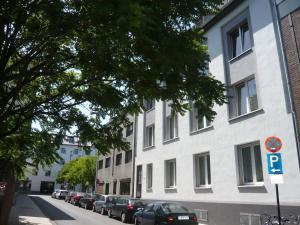 a white building with cars parked on the side of a street at Koelsche Kluengel in Cologne