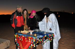 a group of people standing around a table in the desert at Tuareg Luxury Camp in Merzouga