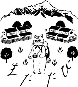 a cat with a camera in front of houses and mountains at ゲストハウスまたたび in Matsumoto