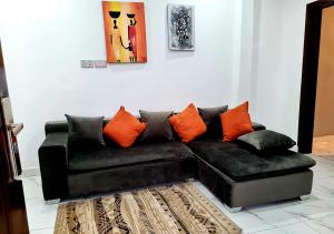a black couch with orange pillows in a living room at Douglas Luxury Apartments At Douglas Court, Adenta, Accra in Accra