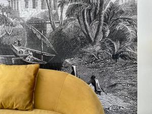a yellow couch with a drawing of a boat at Villa du Palmier in Esquay-sur-Seulles