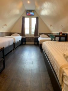 a room with three beds and a tv on the wall at Dam Hotel in Amsterdam