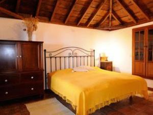 a bedroom with a yellow bed and a wooden dresser at Casa Chamiquela in La Galga