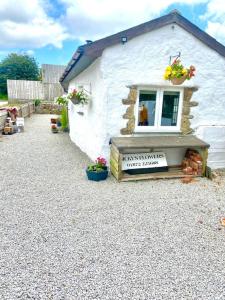 un piccolo edificio bianco con finestra e fiori di Romantic log-burner Cornish Cottage private garden dogs welcome a Truro