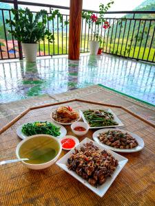 una mesa con platos de comida y tazones de comida en Ba Be Lake View Homestay, en An Ma
