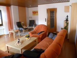 LissendorfにあるEifelferienhaus Thomeのリビングルーム(オレンジ色のソファ、テーブル付)