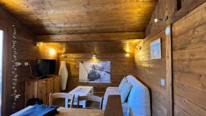 een eetkamer met houten muren en tafels en een tv bij mini duplex dans chalet in Saint-François-Longchamp