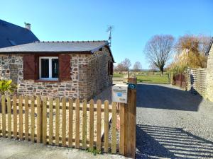 einen Holzzaun vor einem Backsteinhaus in der Unterkunft Maison au pied du Mont Saint Michel in Pontorson