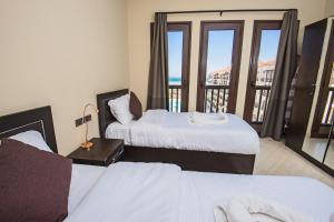 een hotelkamer met twee bedden en een balkon bij Premium sea view 2 bedrooms 2 bathrooms apartment located within Gravity Hotel & Aquapark Hurghada in Hurghada +17 foto's