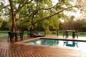 a wooden deck with a table and chairs next to a pool at Malilule Safaris in Hoedspruit