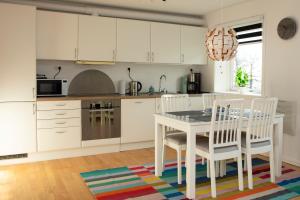 a kitchen with white cabinets and a table and chairs at Mørk Apartments- Great View in Tórshavn